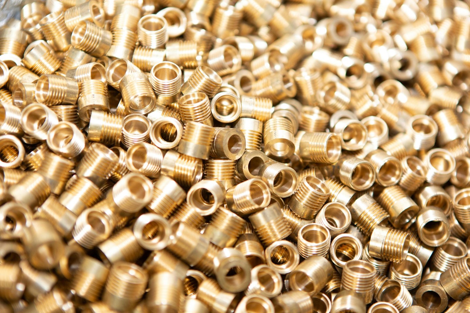 A detailed close-up of a pile of brass screws and nuts with a golden metallic finish.